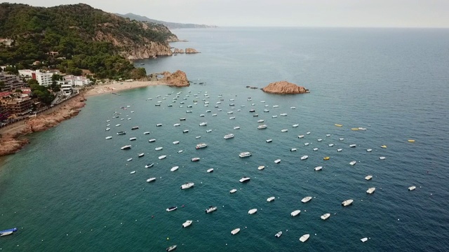 航拍的船只停泊在海面附近的岩石，无人机飞向地平线- Tossa de Mar，西班牙视频素材