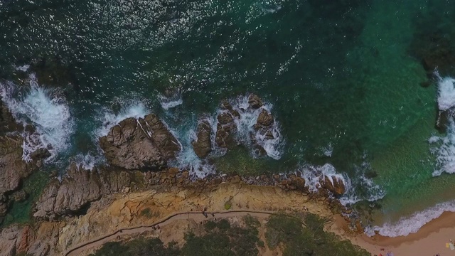 晴朗的一天，空中封锁拍摄海浪拍打在海面上的岩石上，无人机在岩石上上升——西班牙略雷特·德马尔视频素材