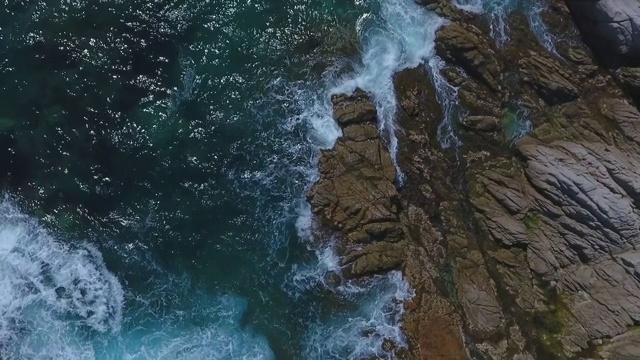 晴朗的一天，空中拍摄海浪拍打在海面上的岩石上，无人机在岩石上飞行——西班牙的略雷特德马尔视频素材