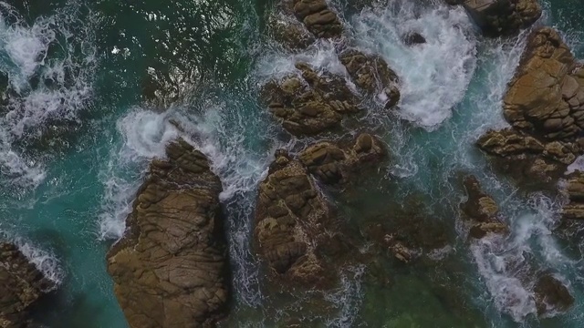 在阳光明媚的日子里，海浪拍打在海上的岩石上的空中鸟瞰图，无人机下降在岩石形成-略雷特德马尔，西班牙视频素材