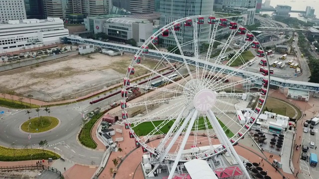 航拍拍摄的人在摩天轮在城市的海上，无人机飞过建筑物的街道-香港，中国视频素材