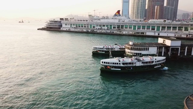 空中平移拍摄的船只在海上由建筑物对天空日落，无人机飞过水城市-香港，中国视频素材