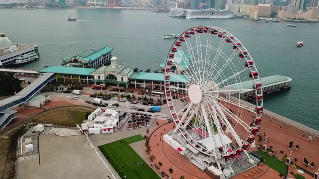 航拍拍摄的游客在摩天轮在城市的海上，无人机飞过建筑物的街道-香港，中国视频素材