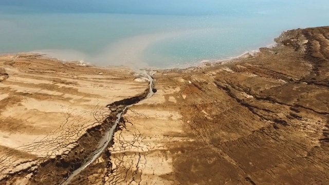 航拍水流经峡谷在盐湖，无人机飞向死海在晴朗的一天视频素材