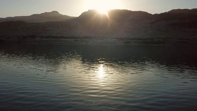 在日落时分，无人机在以色列著名的自然地标——死海上空拍摄的靠近山脉的盐湖视频素材