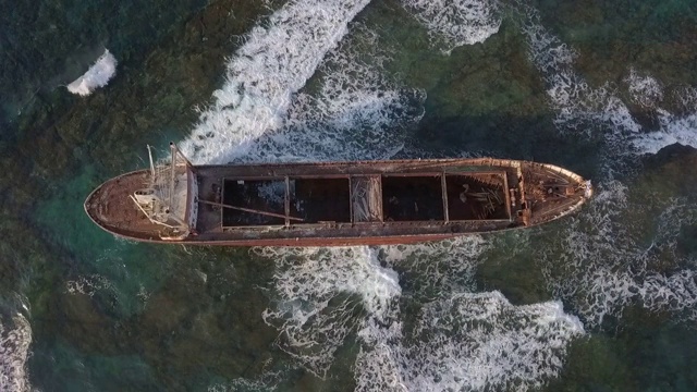 空中倾斜拍摄的废弃货船残骸在阳光明媚的一天，无人机下降在海难中海浪-帕福斯，塞浦路斯视频素材