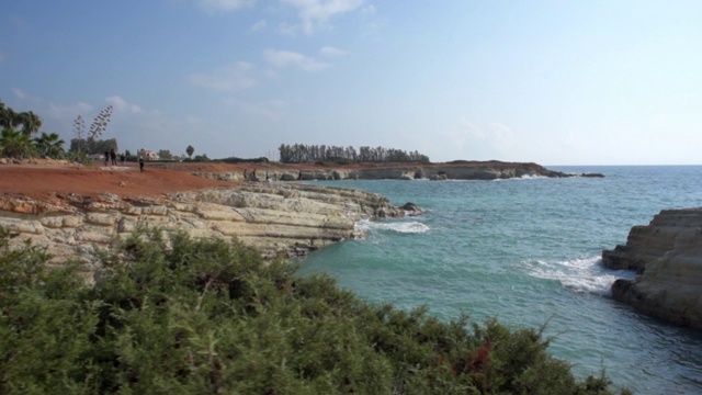 在塞浦路斯岛帕福斯，阳光明媚的日子里，在海上的岩石悬崖上拍摄人和植物视频素材