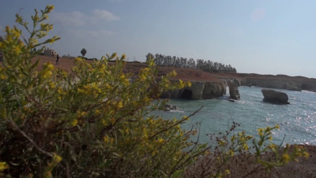 在塞浦路斯岛帕福斯，阳光明媚的日子里，从海上对着天空摇摄岩石悬崖上的人们视频素材