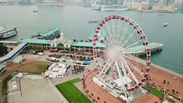 在沿海城市的海边，人们在空中摇摄摩天轮，无人机飞过建筑物-中国香港视频素材