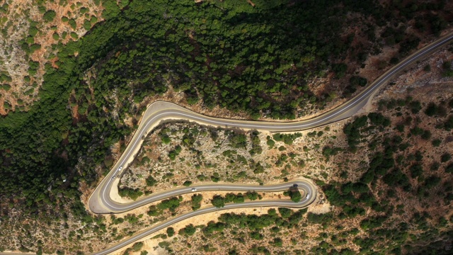 鸟瞰图上的车辆在绿色植物中蜿蜒的道路上，无人机飞过风景-克舍特洞穴，以色列视频素材