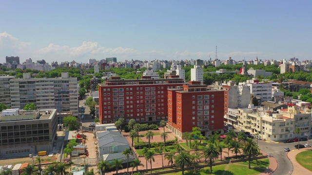 在阳光明媚的一天，无人机向后飞行在城市建筑上空的城市拍摄的城市景观-蒙得维的亚，乌拉圭视频素材