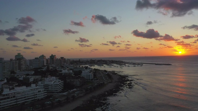 航拍城市的海滩对天空在日落，无人机飞越海洋-埃斯特角，乌拉圭视频素材