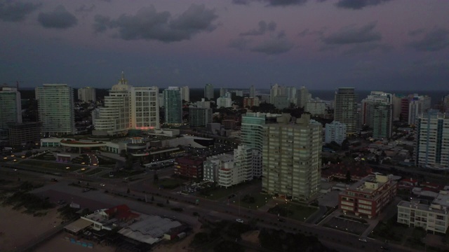 空中拍摄的城市在黄昏的天空，无人机飞过建筑物-埃斯特角，乌拉圭视频素材