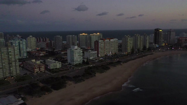 航拍城市的建筑物在黄昏的海滩，无人机向前飞行的海洋-埃斯特角，乌拉圭视频素材