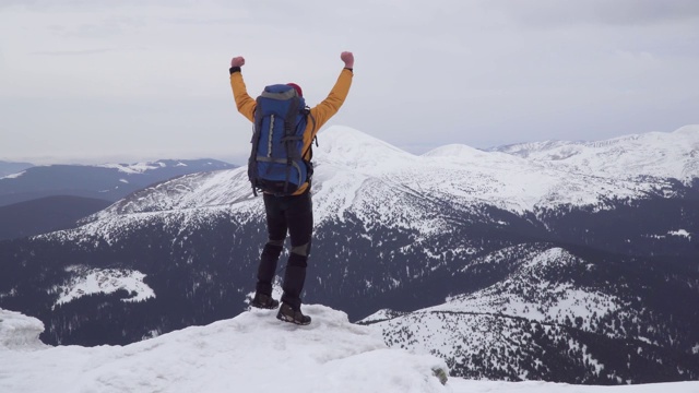 一个背着背包的男人冬天在山里旅行视频素材