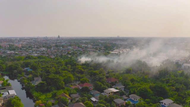 从空中看到的烟雾从燃烧在森林与绿色的树木在曼谷市，泰国。自然景观背景中的空气污染和环境概念。全球变暖视频素材