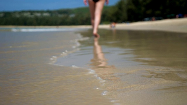 赤脚女士走在空旷的海洋海滩下的蓝天视频素材