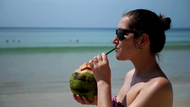 海滩上的女人喝椰子酒视频素材