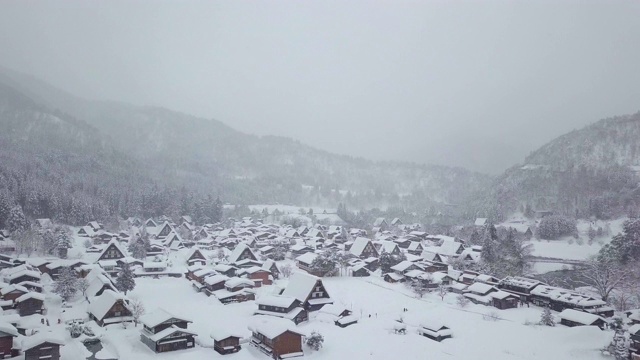 白川乡(Shirakawa-go)的传统茅草屋位于日本岐阜县(Gifu)、石川县(Ishikawa)和富山县(Toyama)附近的雪山中视频素材