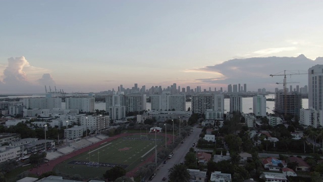 空中平移拍摄的城市与体育场附近的天空，无人机在日落时飞过建筑物，体育场的鸟瞰图视频素材