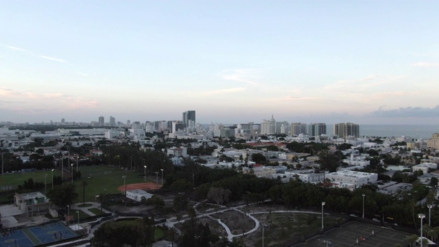 空中平移拍摄的体育场馆在城市的建筑对天空，无人机飞过城市景观在日落，体育场鸟瞰图视频素材