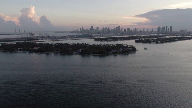 空中倾斜拍摄的船只在海上岛屿附近的天空，无人机从城市向后飞行在日落，海上的船只鸟瞰图视频素材