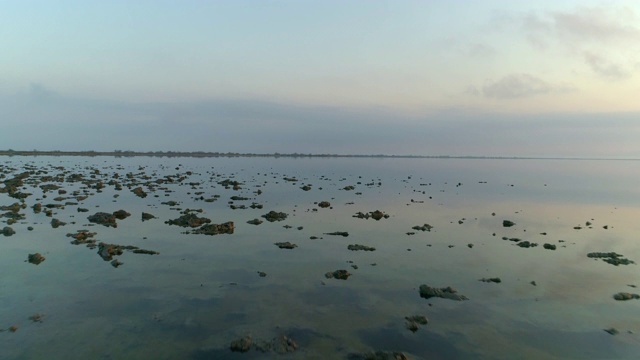 航拍的平静的海与反射在日落的天空，无人机在水上向前飞行-卡马格，法国视频素材