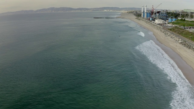 空中倾斜拍摄人们在绿松石海冲浪的城市，无人机飞越海岸线-曼哈顿海滩，加利福尼亚视频素材