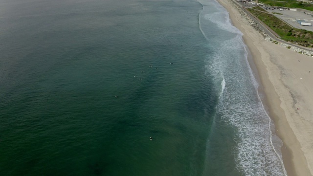 空中倾斜向下拍摄人们在绿松石海的海浪上冲浪，无人机向前飞行的水-曼哈顿海滩，加利福尼亚视频素材