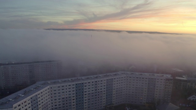 航拍的城市建筑在雾天日落，无人机是向后飞行-埃尔福特，德国视频素材