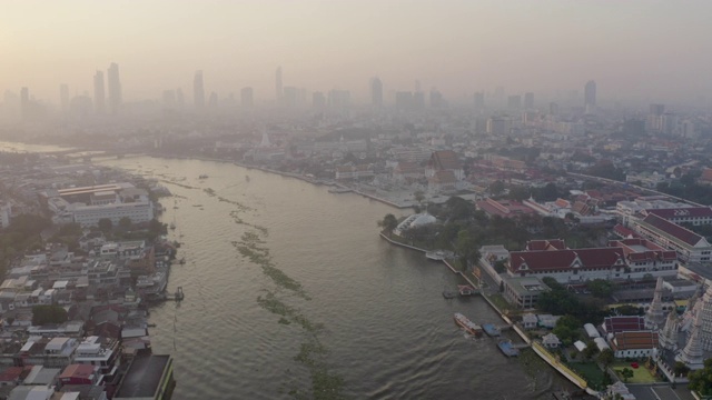 空中平移拍摄的河流在城市的建筑物对天空，无人机飞行附近著名的佛教寺庙日落-曼谷，泰国视频素材