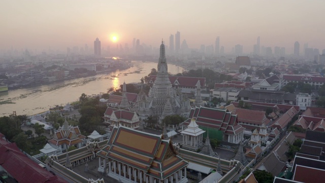 空中平移拍摄的佛教寺庙在城市的河流在日落，无人机从著名的地标对天空-曼谷，泰国视频素材