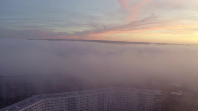 航拍向前拍摄的建筑物在城市对天空日落，无人机正在飞向前在雾天气-埃尔福特，德国视频素材