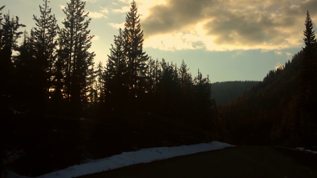 在日落时分的天空中，在树林和雪地里的道路上拍摄的车辆-曼宁公园，加拿大视频素材