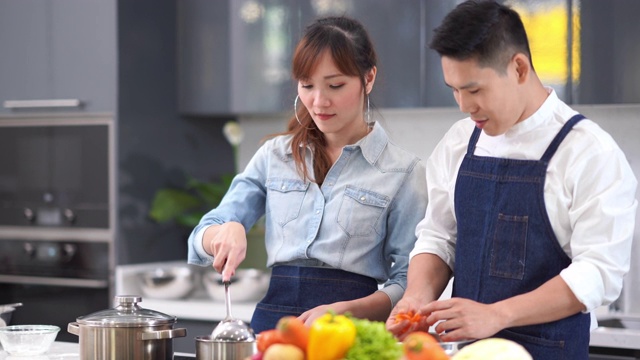 亚洲年轻夫妇在自家厨房做饭视频素材