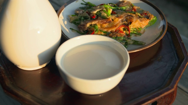 餐盘上放着“Sanseong Makgeolli”和“Jeon”(用平底锅煎的美食)视频素材