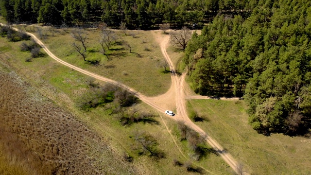 空中俯瞰森林中白色汽车行驶在乡村道路上的全高清视图视频素材