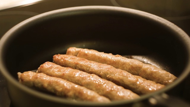 特写肉香肠在煎锅里煎。的概念。香肠在平底锅里煎的特写。在煤气炉上放上油视频素材