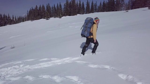 一个背着背包的男人冬天在山里旅行视频素材