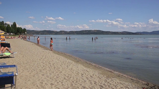 这是意大利Sualzo海滩上的游客和在Trasimeno湖上踩踏板的照片视频下载