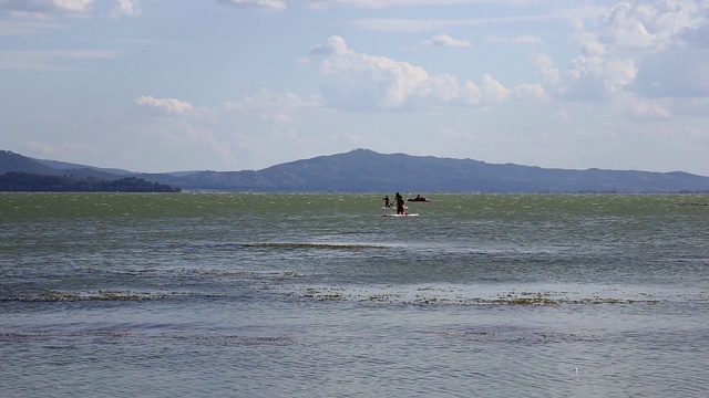这是意大利Sualzo海滩上的游客和在Trasimeno湖上踩踏板的照片视频下载