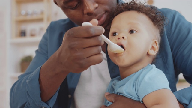年轻的非洲人喂养快乐的婴儿视频素材