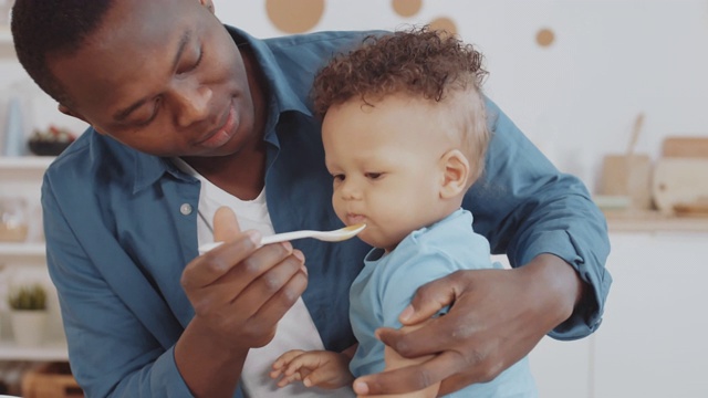 年轻的非洲男子正在喂养婴儿视频素材