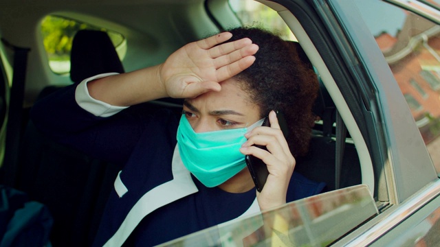 戴着防护面具在车里打电话的女人视频素材