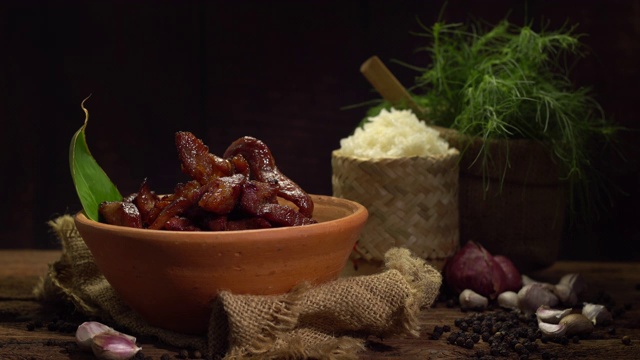 用酱料、大蒜和胡椒制成的猪肉片油炸而成，与糯米或蒸饭一起食用的美味菜肴。选择性的焦点和自由空间的文本。视频素材