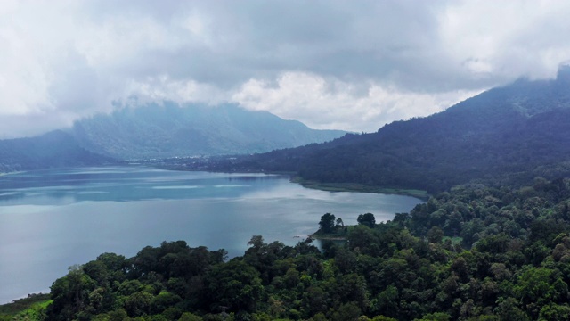 印尼巴厘岛阿贡火山脚下的巴图尔湖鸟瞰图。无人机飞过云雾雨林山视频素材