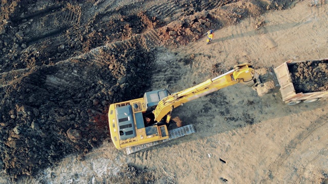 现代建筑工业的挖土机用沙子装载一辆卡车。工业建筑工地的重型机械。视频素材