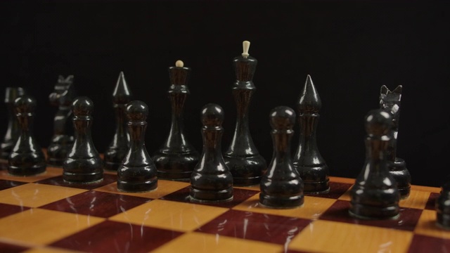 在开始位置的一个棋盘上的木制的黑色棋子的宽镜头视频素材