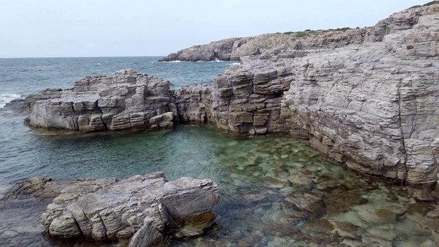 美丽的岩石湾景观与巨大的悬崖俯瞰大海和水晶清澈的水，在意大利撒丁岛地区的圣彼得罗岛，一个奇妙的旅游目的地视频素材