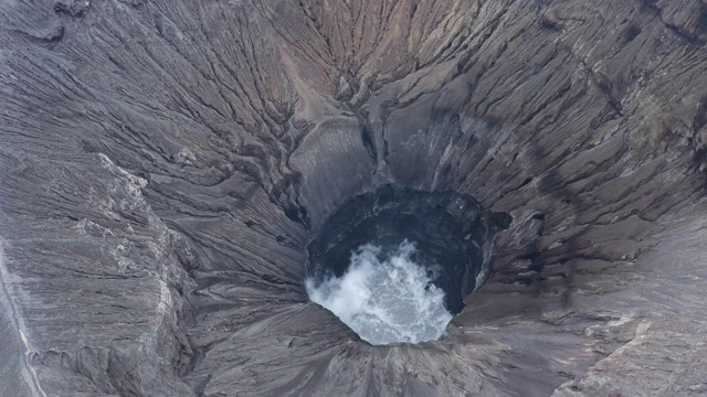 从上面俯瞰，令人惊叹的布罗莫火山鸟瞰图和从火山口升起的气体云。视频素材